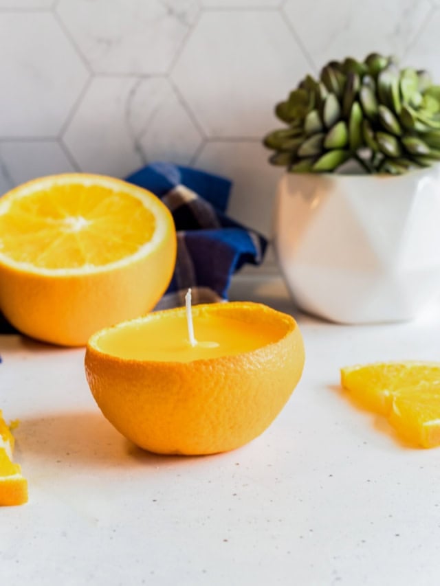 Citrus peel candle made from orange peel with lemon slices in the background.
