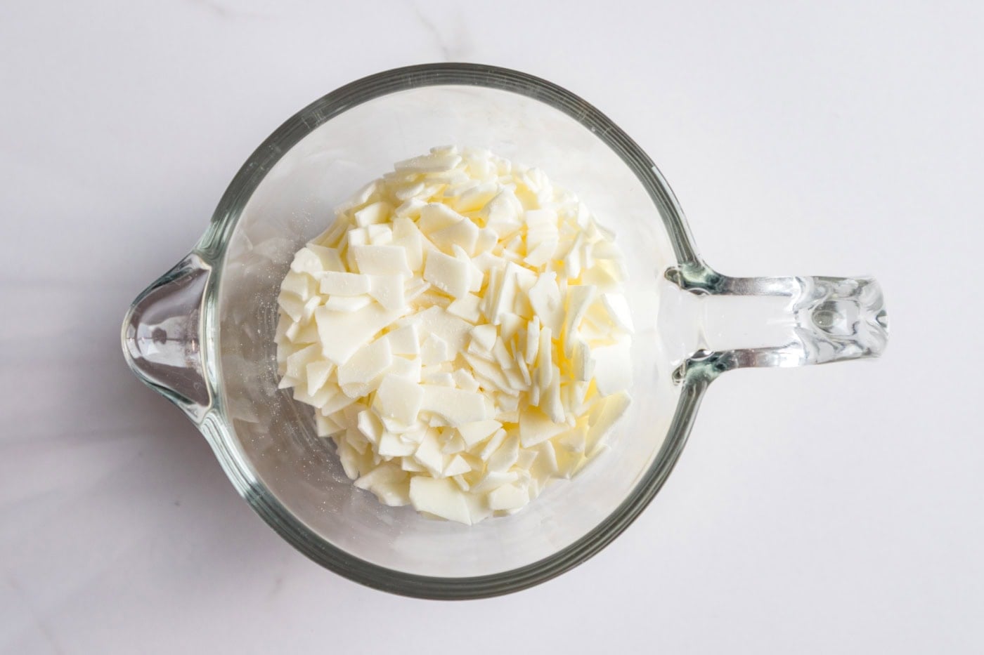 Close-up of soy wax flakes in a glass measuring cup for making citrus peel candles.