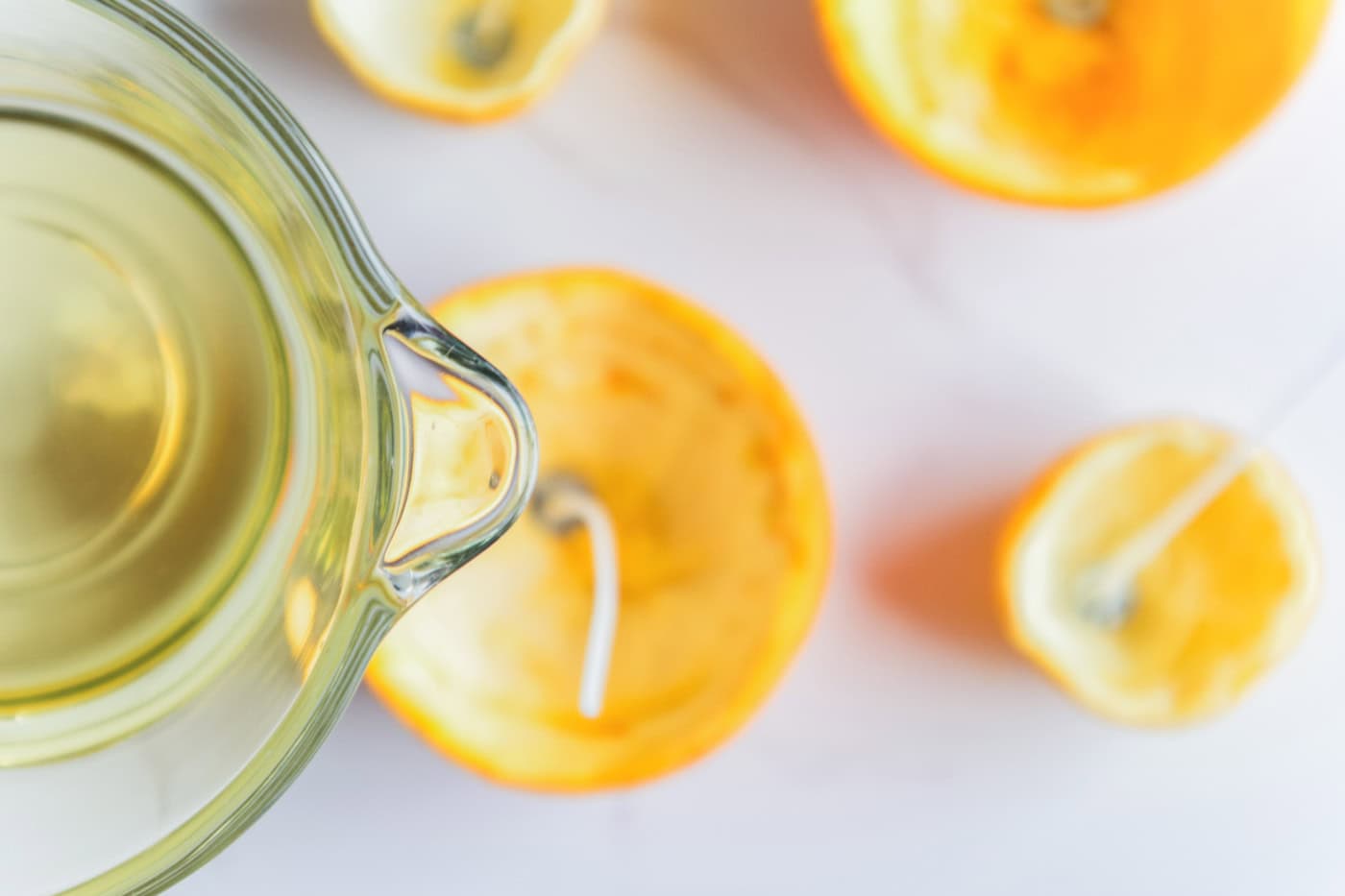 Melted soy wax being poured into prepared orange and lemon peel candle containers.