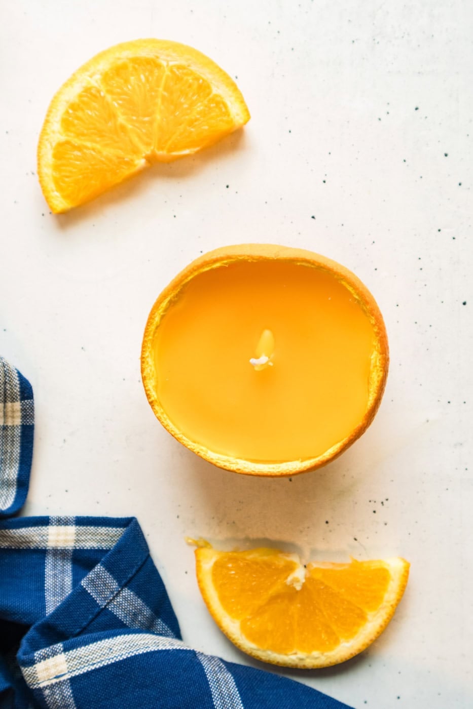 Top view of a finished orange peel soy candle surrounded by fresh orange slices.
