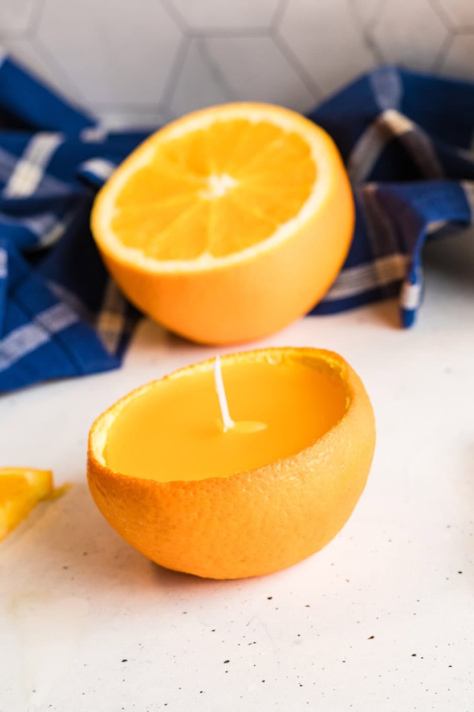 Overhead close-up of a DIY orange peel candle with smooth wax and a short trimmed wick.