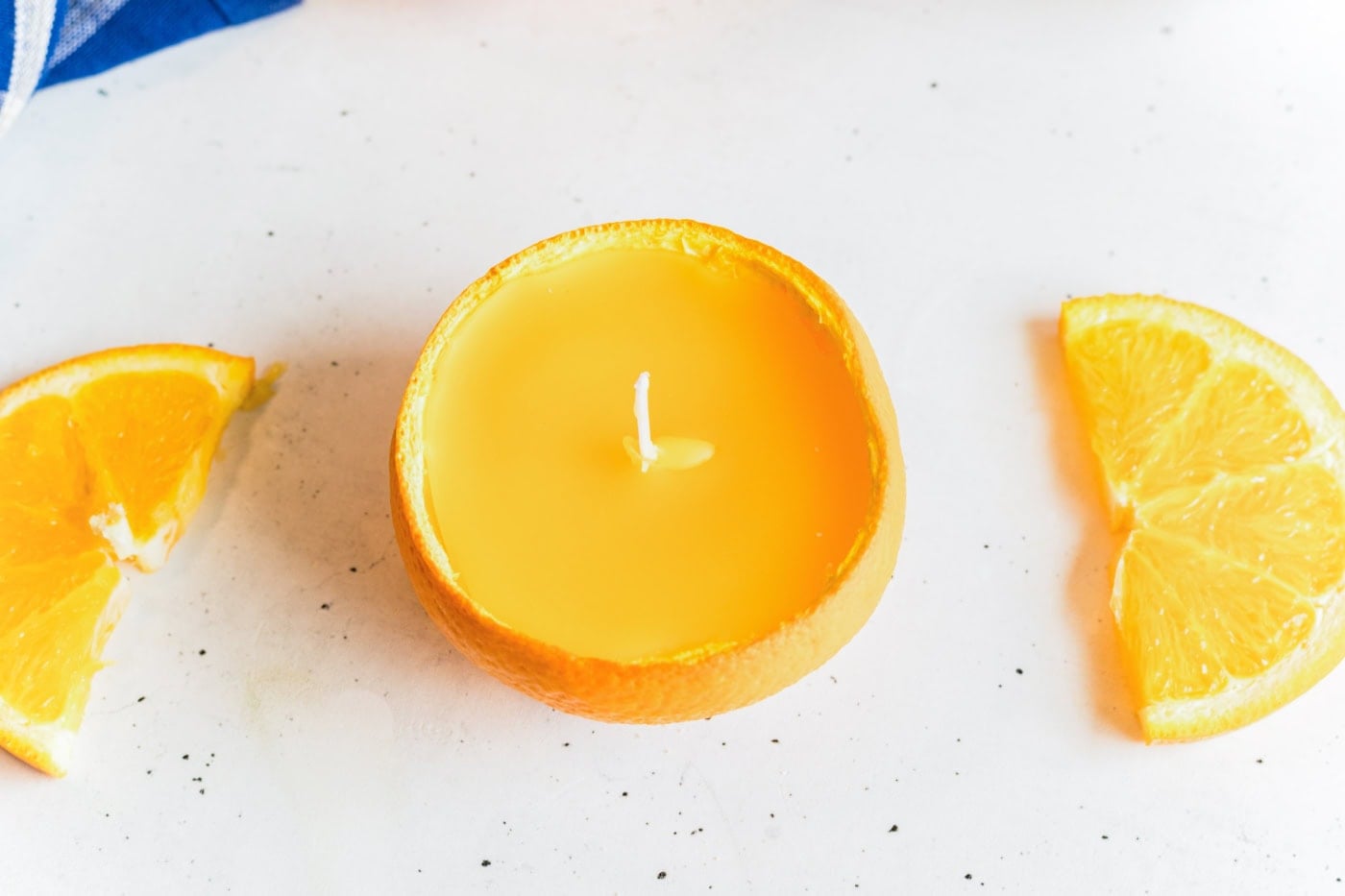 Finished orange peel candle filled with soy wax and styled with fresh orange wedges.