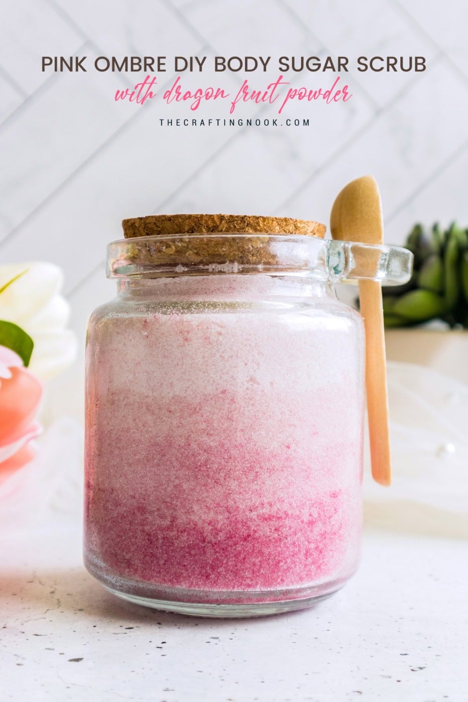 Pink ombre DIY body sugar scrub in glass jar with wooden spoon and cork lid.