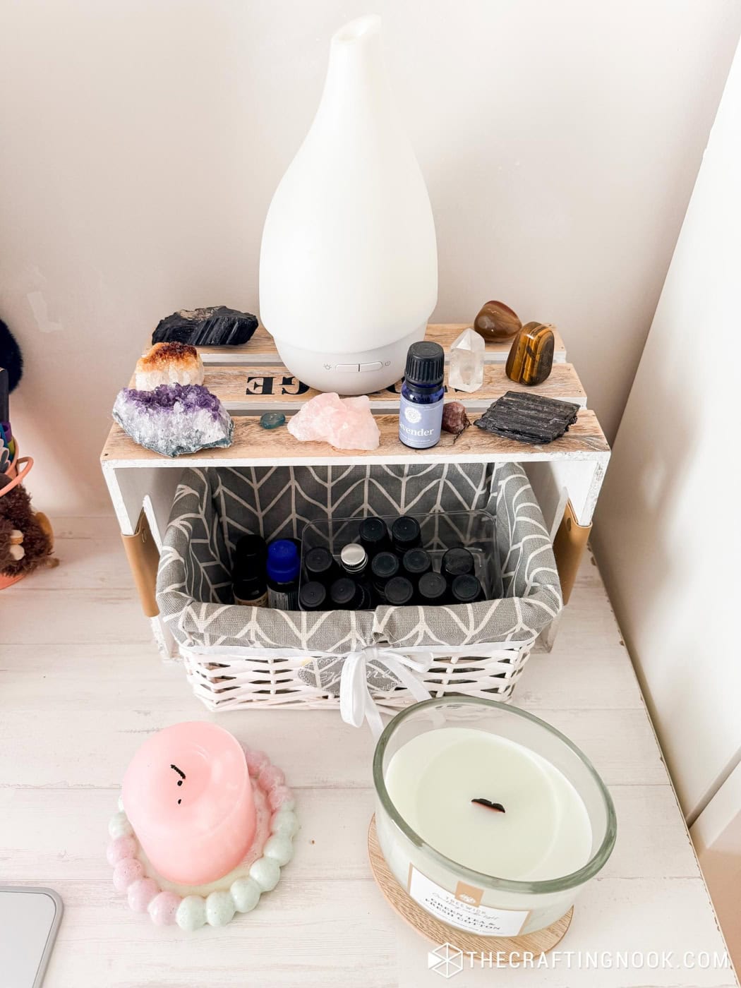 Close-up of crystals, an essential oil diffuser, and a lavender oil bottle on a wood crate shelf