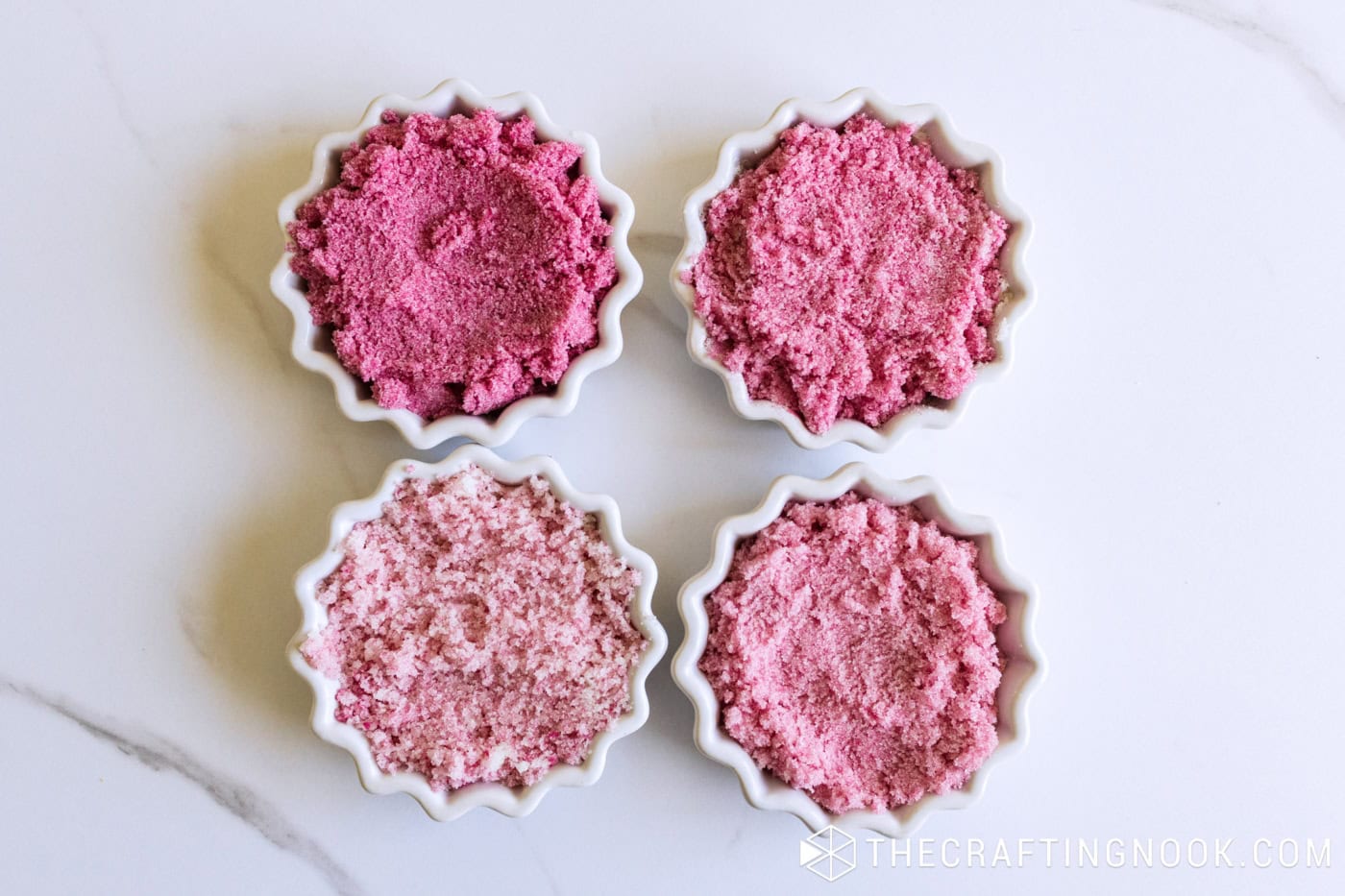 Four bowls of mixed sugar scrub in shades of pink, from light to deep