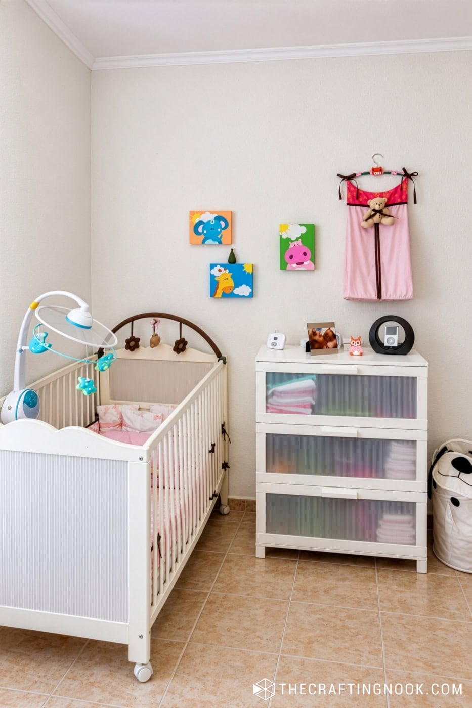 Baby nursery with crib, changing dresser, and handmade diaper stacker hanging on the wall