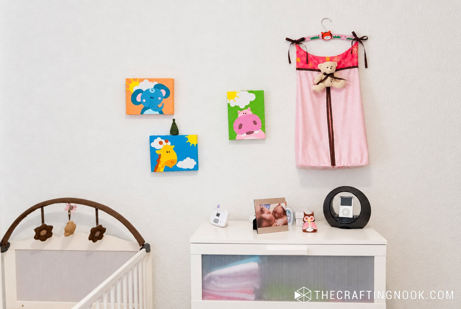 Pink hanging diaper stacker displayed on the nursery wall beside the changing area
