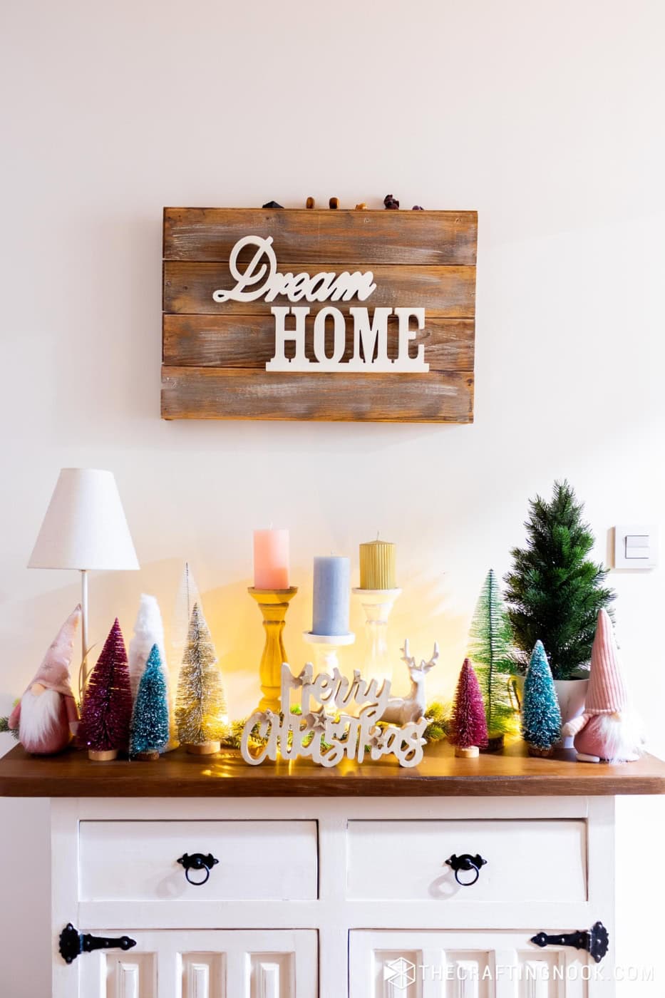 Dream Home wooden sign above a white console with bottle brush trees, candles and a Merry Christmas sign