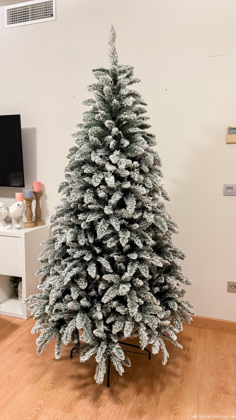 Full and bushy artificial flocked Christmas tree with snow-covered branches before adding lights and ornaments.