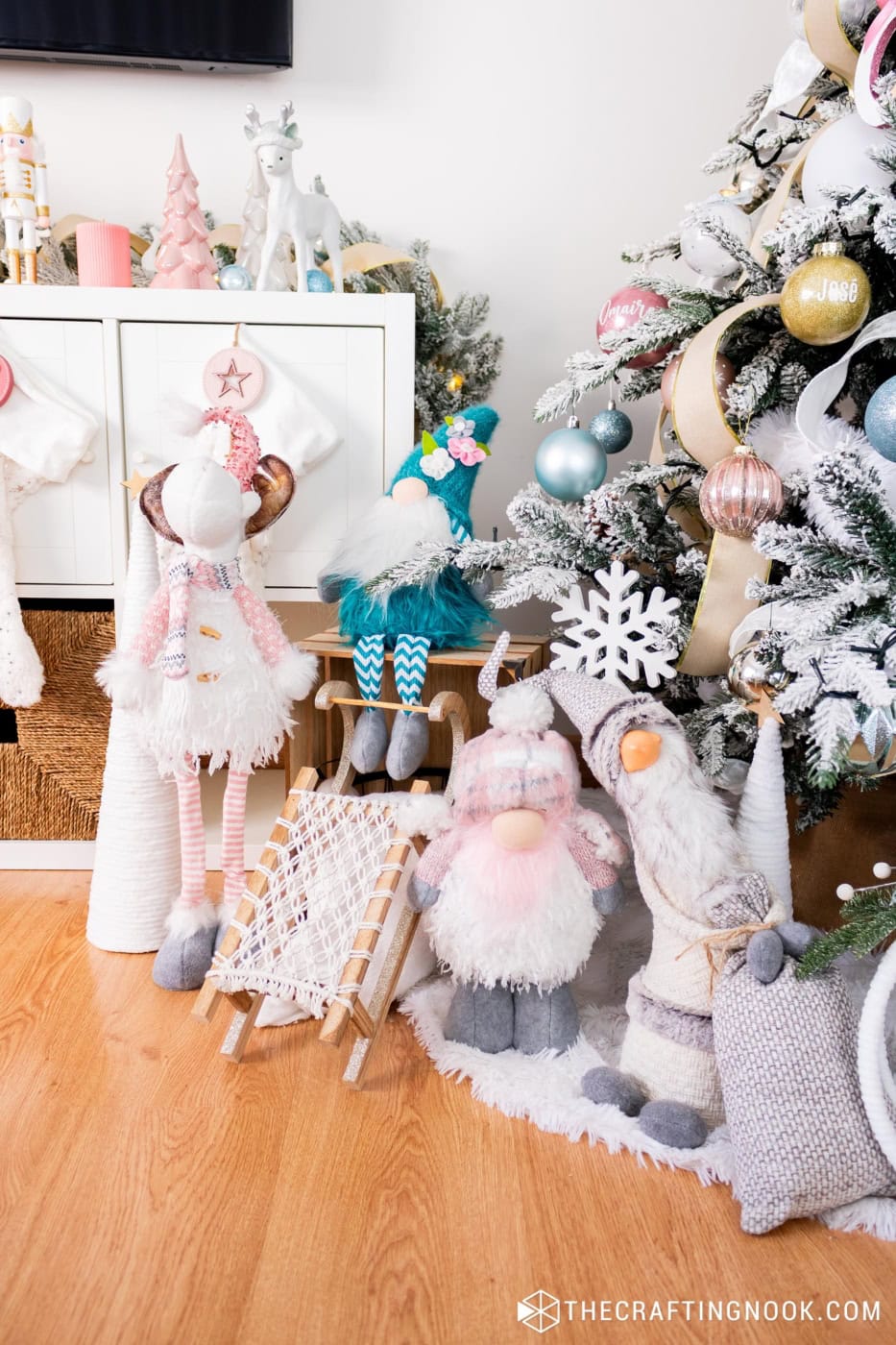 Plush reindeer, gnomes and a small wooden sled under the Christmas tree on a white fur tree skirt