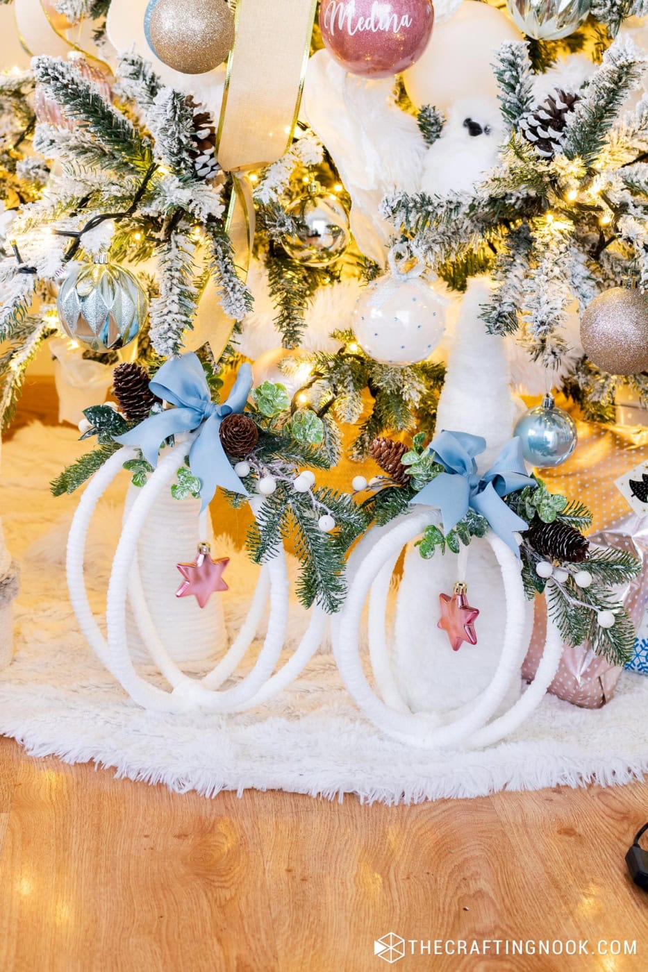 White wrapped hoop decorations with blue bows, pine, pinecones and pink stars under the tree
